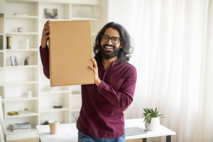 Delivery Concept. Excited Young Indian Man Embracing Big Delivered Box At Home, Cheerful Millennial Eastern Man Holding Parcel With Ordered Items, Emotionally Reacting To Fast Shipping, Copy Space